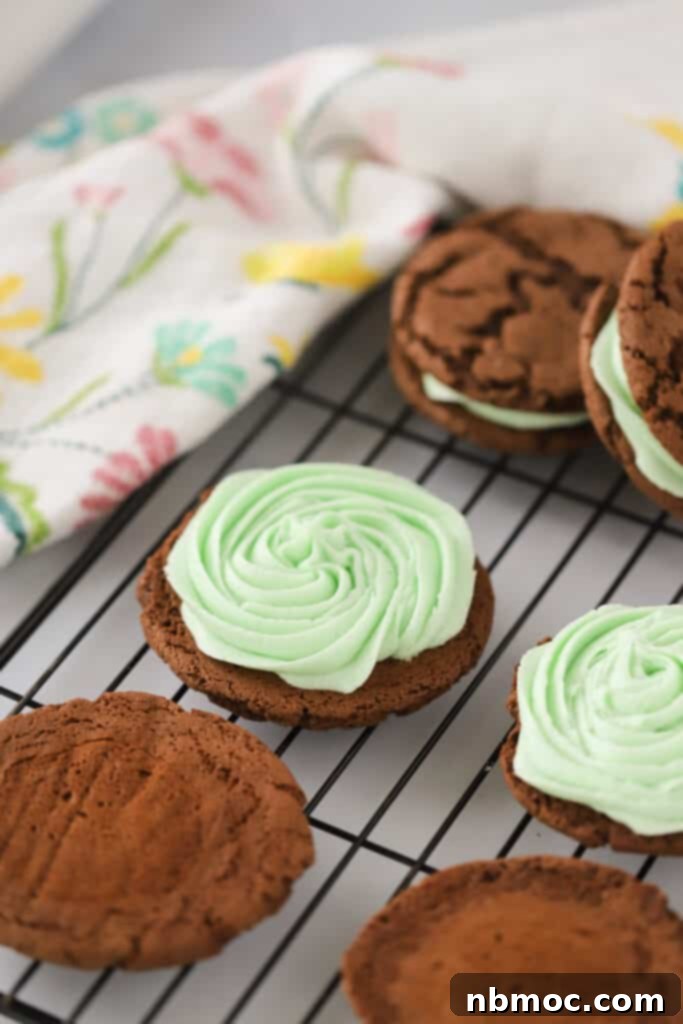 Chocolate cookie sandwiches filled with Mint Cream Cheese Frosting on a wire rack. Buttercream mint frosting. Mint Icing.
