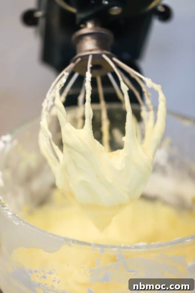 A stand mixer with a whisk making lemon cream cheese frosting recipe, a favorite recipe for lemon cream cheese frosting.