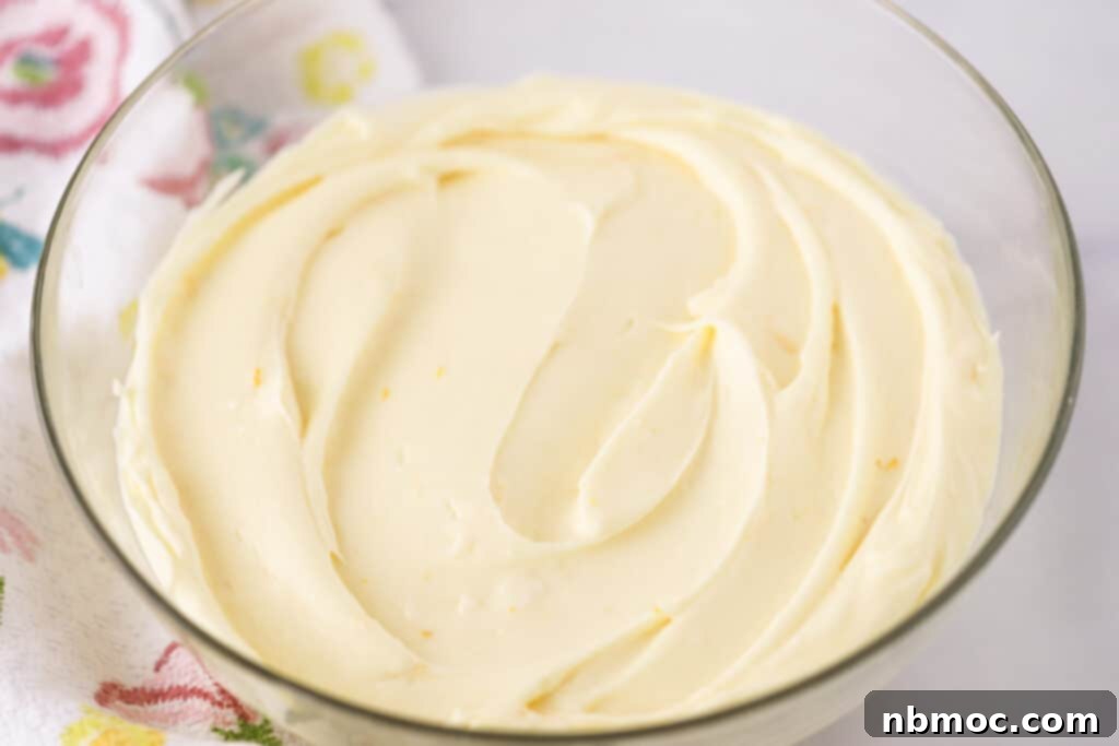 a large glass mixing bowl full of Lemon Cream Cheese Frosting, lemon frosting cream cheese, lemon cream cheese frosting recipe, lemon cream.cheese frosting.