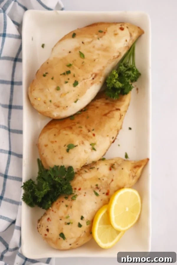 Baked Lemon Chicken on a plate; best baked lemon chicken recipe. A serving of lemon ginger chicken with fresh lemon slices and herbs.