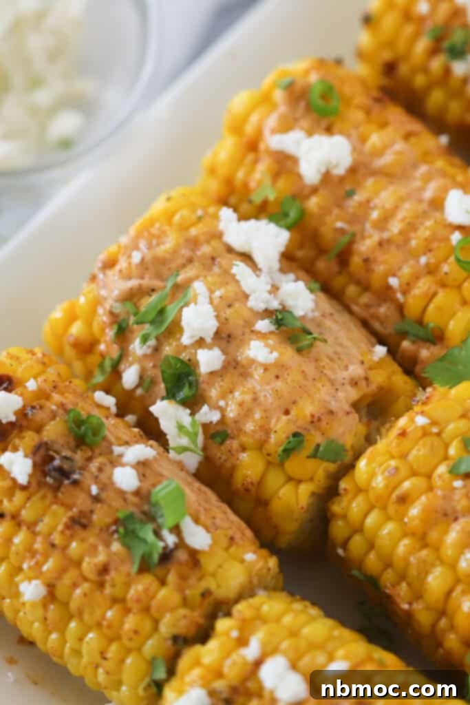 A plate with grilled Mexican street corn topped with cotija cheese, lime crema, and fresh cilantro.