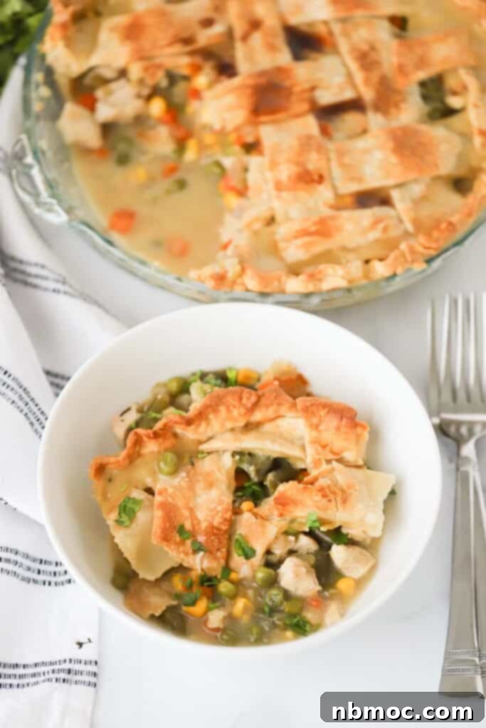 A bowl with a portion of old fashioned chicken pot pie and the full pie in the background.