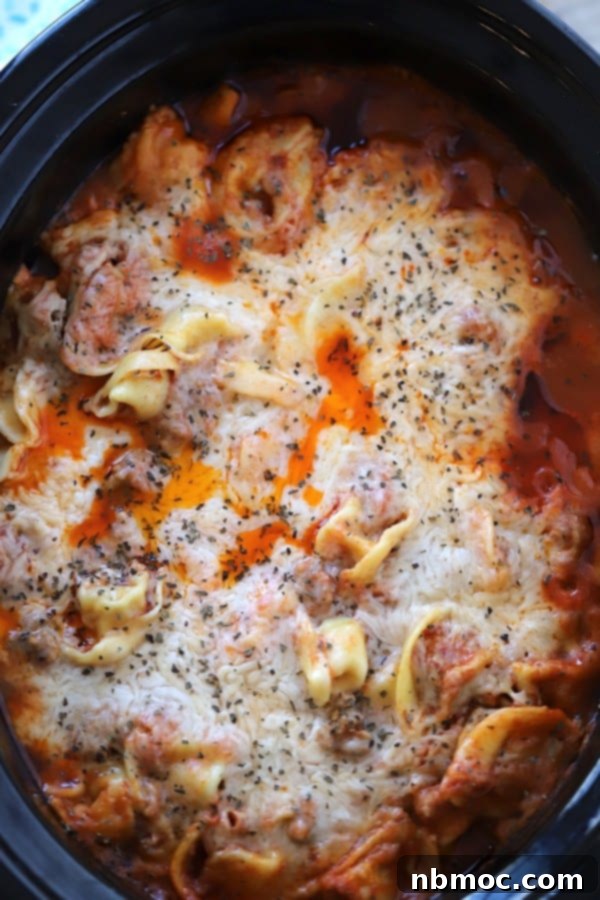Cheesy Slow Cooker Tortellini Bake 2 A crockpot full of slow cooker tortellini and marinara sauce all covered with melted cheese.