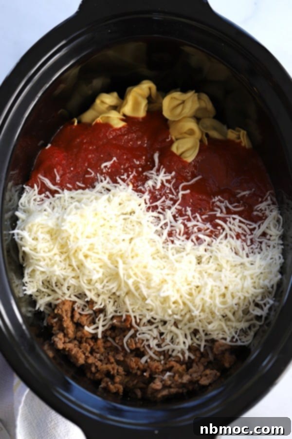 Cheesy Slow Cooker Tortellini Bake 3 A slow cooker with tortellini, marinara, cheese, and beef all ready to cook.
