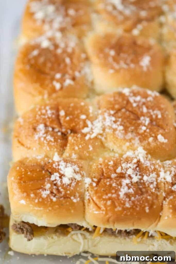 A slab of hawaiian roll cheeseburger sliders on a baking sheet, ready to be served.