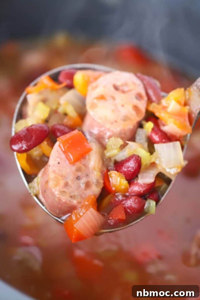 A large ladle full of slow cooker red beans and sausage.