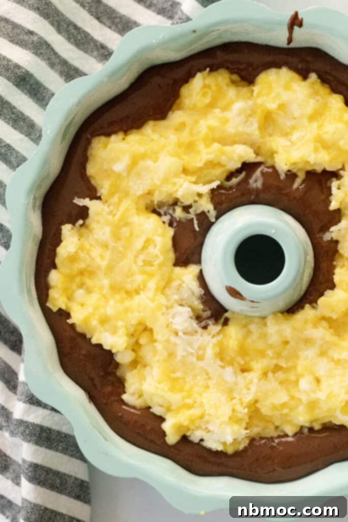 A bundt pan with chocolate cake batter and coconut filling in the center ready to bake.