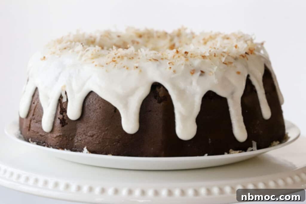 chocolate bundt cake with coconut filling on platter with almond glaze dripping down the sides.
