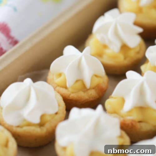 Banana Dream Cookie Cups 6 A close-up shot of a single banana cream pie cookie cup, topped with whipped cream and a small banana slice.