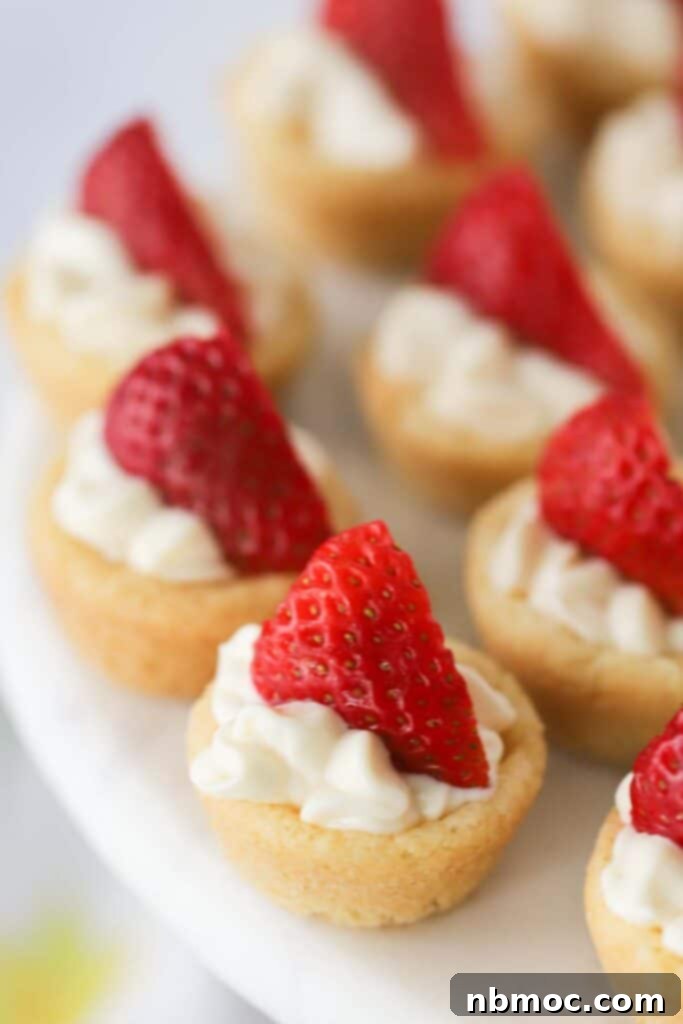 A platter full of lemon cream cheese cookies topped with whipped cream and sliced strawberries.