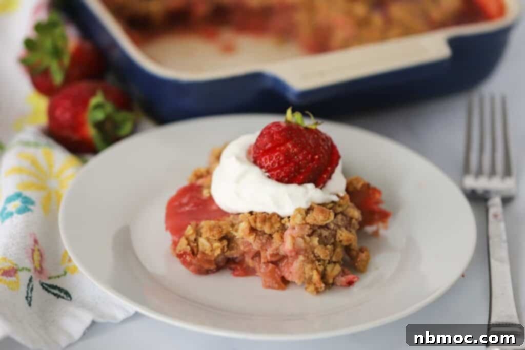 Sweet and Tangy Strawberry Rhubarb Crisp 5 A plate with a serving of rhubarb crisp with oats on top and whipped cream.