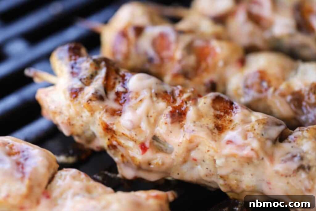 Close-up of bang bang chicken skewers cooking on the grill, showing the delicious caramelization.