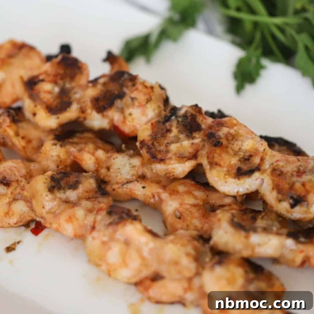 Grilled Bang Bang Shrimp Kabobs 2 Grilled Bang Bang shrimp skewers artfully arranged on a serving plate, drizzled with sauce.