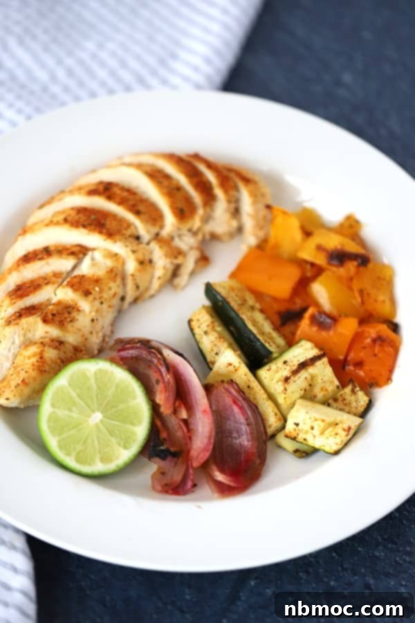 Zesty Chili Lime Sheet Pan Chicken and Veggies 5 A white serving place with sliced chicken and cooked sheet pan veggies.