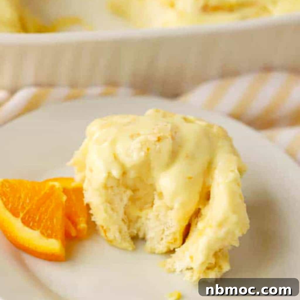 Homemade orange sweet rolls generously topped with vibrant orange creamsicle frosting.