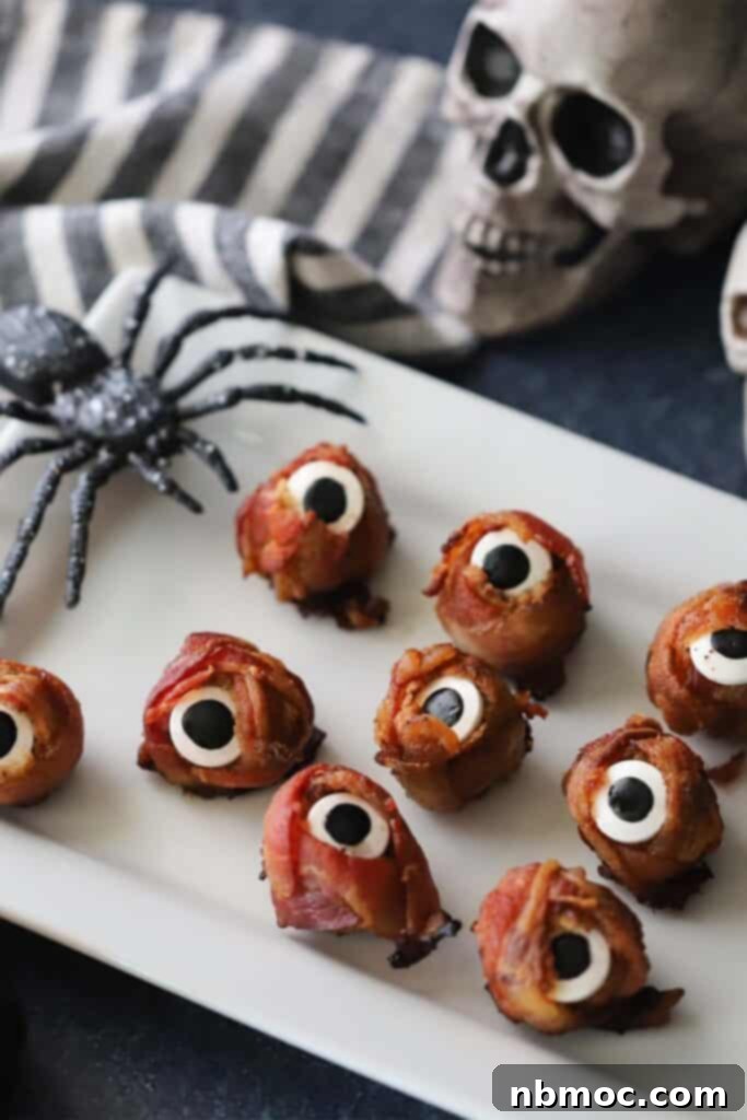 A plate full of Halloween mummy meatballs wrapped with bacon, looking like spooky eyeballs.