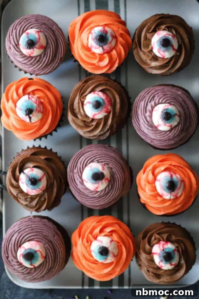 a baking sheet filled with easy halloween cupcakes decorated with candy eyeballs and frosting.