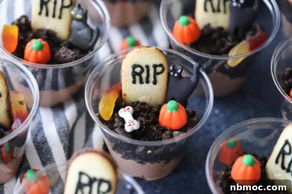Haunted Earth Pudding Cups 5 Dirt cups for halloween on a tabletop, decorated with gravestone cookies and halloween candies. Multiple cups are visible, ready for a party.
