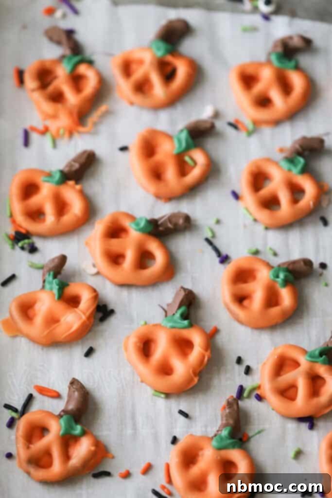 Spiced Pumpkin Pretzel Twists 2 Festive Halloween pumpkin pretzels, meticulously decorated with orange chocolate and green leaves, cooling on a sheet tray, ready for serving.