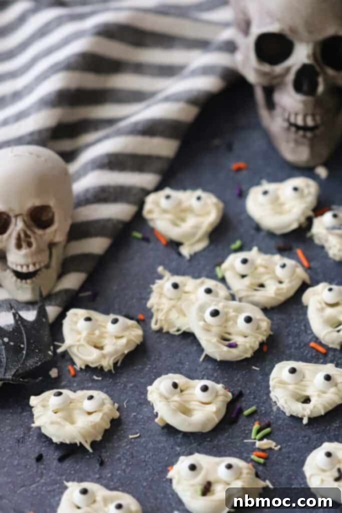 A table display with halloween chocolate dipped pretzels drizzled with white chocolate to look like mummies.
