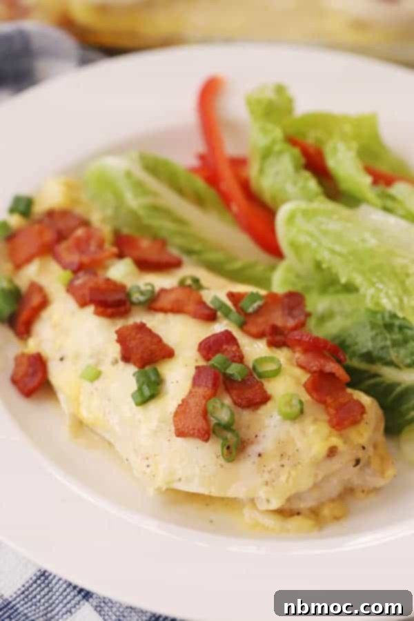 A plate featuring easy baked honey mustard chicken, garnished with crispy bacon bits, fresh sliced green onions, and accompanied by a fresh side salad.