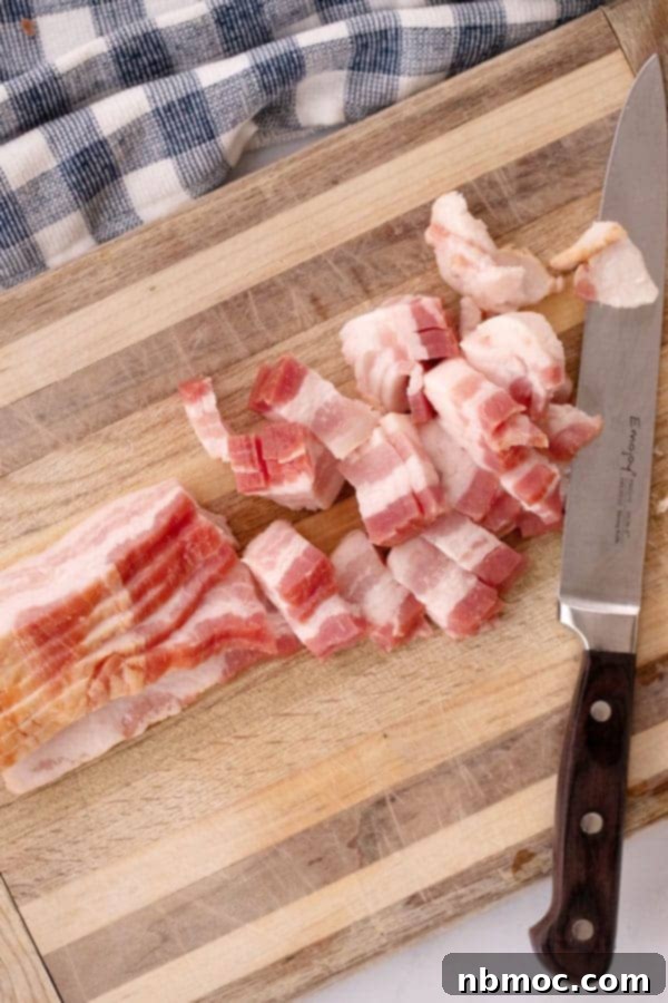 Slices of bacon being expertly cut on a wooden cutting board with a sharp knife, preparing them to be transformed into crispy bacon bits.