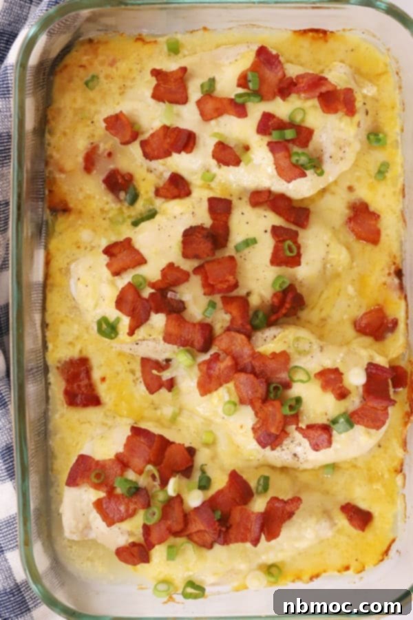 Golden-brown baked chicken, rich with mustard sauce and bacon bits, resting in a pristine white baking dish, ready to be served.
