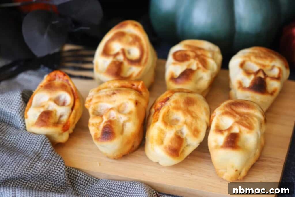 Best halloween pizza ideas include these pizza skulls, resting on a wooden cutting board. Individual skull pizzas with golden crust and melted cheese, perfect for a spooky party.