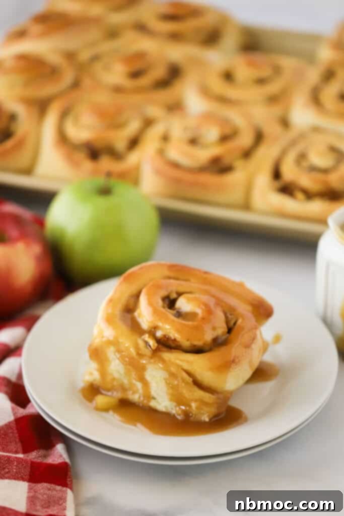 Gooey homemade Caramel Apple Cinnamon Rolls on a white plate, perfect for a fall breakfast or brunch.