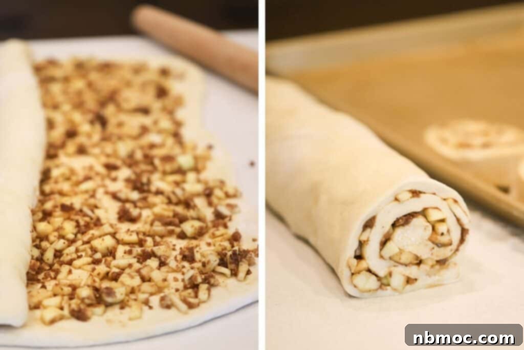 Apple cinnamon filling spread on dough, being rolled up to form cinnamon rolls.