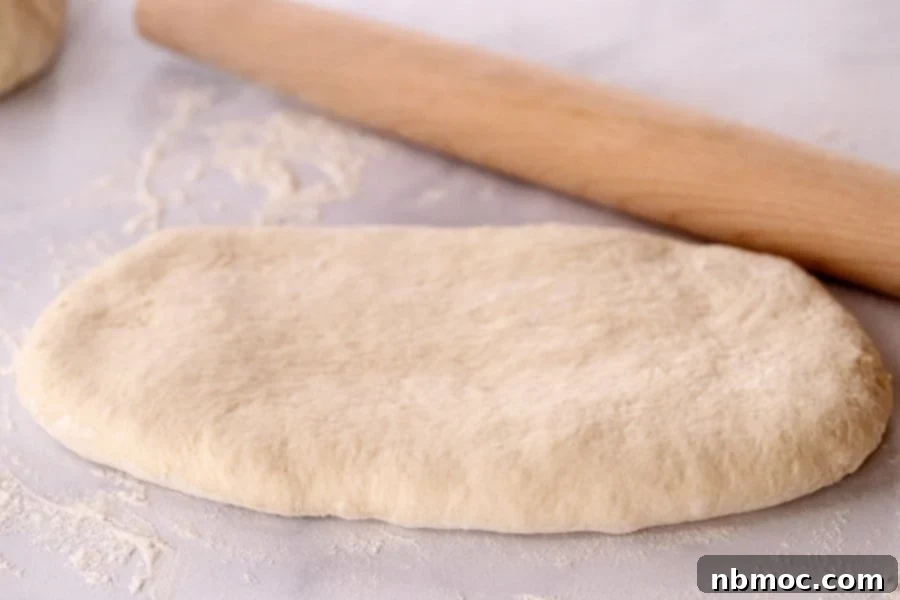 Bread dough and wooden rolling pin on floured counter top.