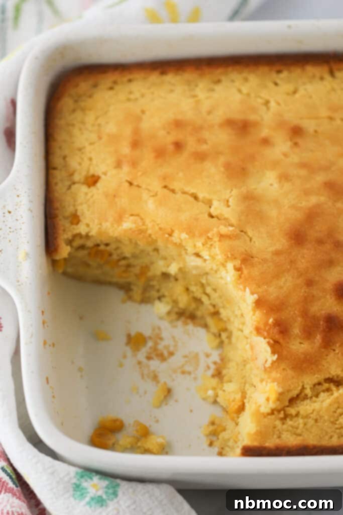 A baking dish full of cornbread pudding casserole made with creamed corn, cornbread, and corn kernels, highlighting its rich, golden-brown crust.