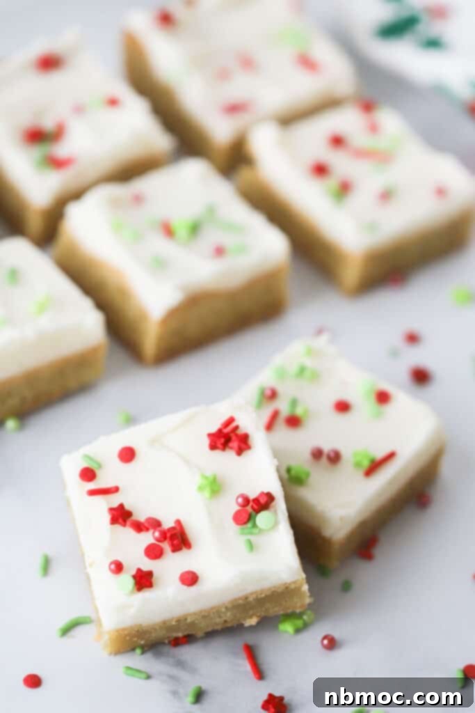 Rows of festive Christmas Sugar Cookie Bars topped with creamy buttercream frosting and colorful holiday sprinkles, ready to be enjoyed.