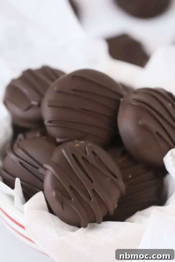 Close-up of a stack of freshly made Homemade Peppermint Patties, showcasing their smooth dark chocolate coating and creamy white interior.