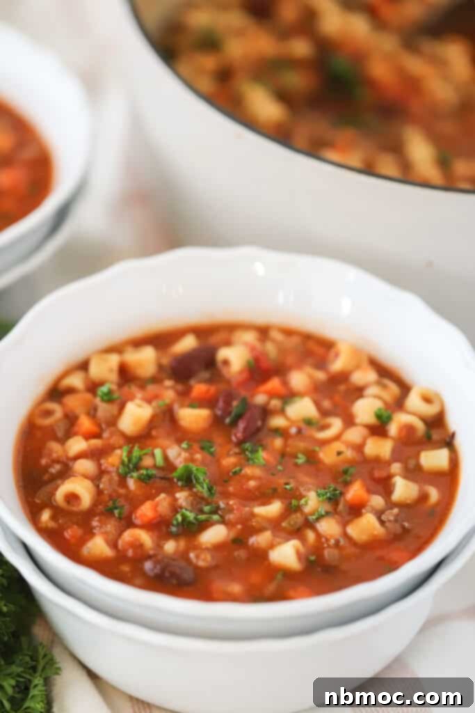 A serving bowl full of hearty pasta fagioli soup made with canned beans and ground beef.