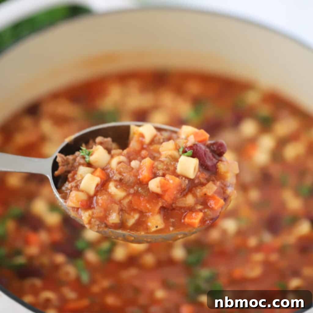 A spoon holding pasta e fagioli soup, a homemade italian soup that tastes better than the pasta fagioli soup at olive garden. Recipe fagioli soup.