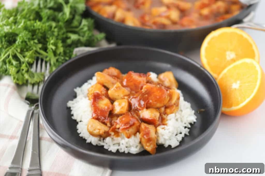 A plate with sticky orange chicken served over white rice. This is the best homemade orange chicken recipe.