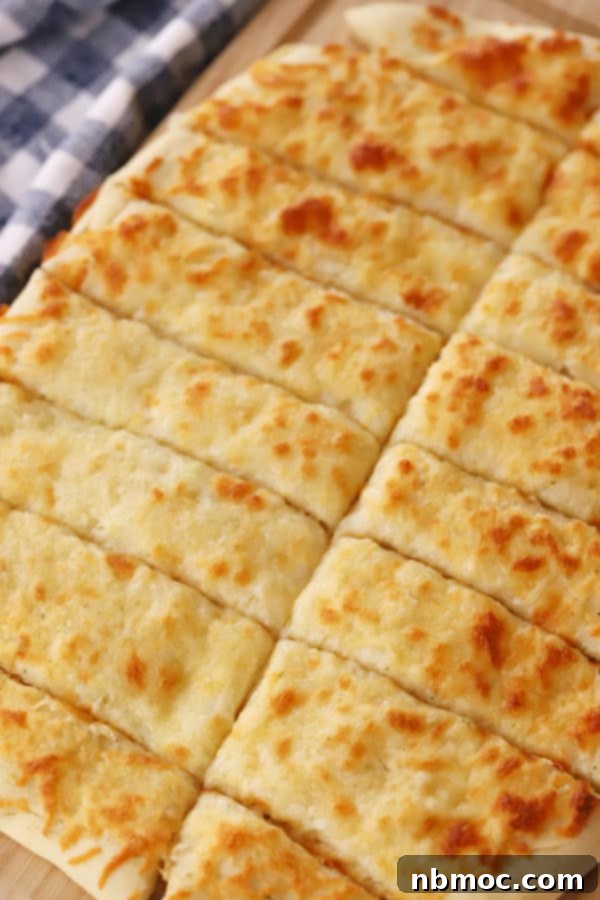 Golden-brown homemade cheesy breadsticks cut into slices, ready to be served as an appetizer.