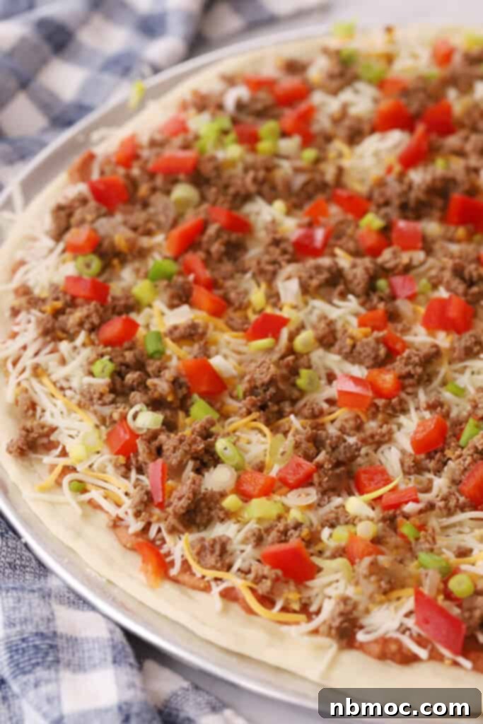 Fiesta Taco Pizza 4 A pizza on a pizza pan ready to bake, topped with taco toppings.