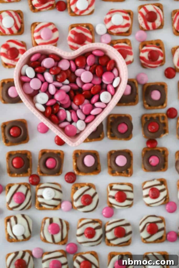 A tray full of Valentine's Day themed Hershey Kiss Pretzels bites made with M&Ms and small square pretzels. Pretzel kisses m&m bites.