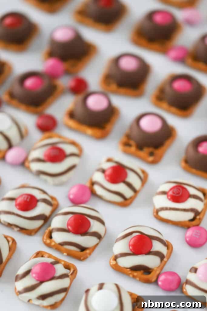 Hershey Kiss Pretzel M&M Bites topped with pink and red M&Ms for Valentine's Day. Pretzel kiss M&Ms, pretzels with hershey kisses and m&ms.