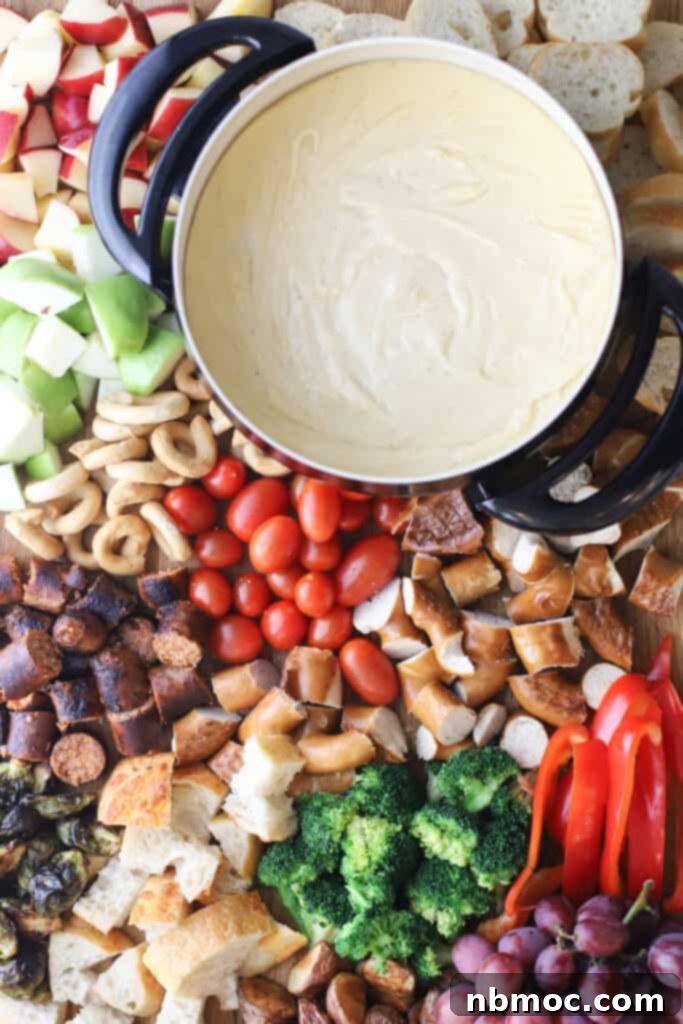 classic cheese fondue in a small pot surrounded by cheese fondue dippers. An easy fondue cheese recipe.