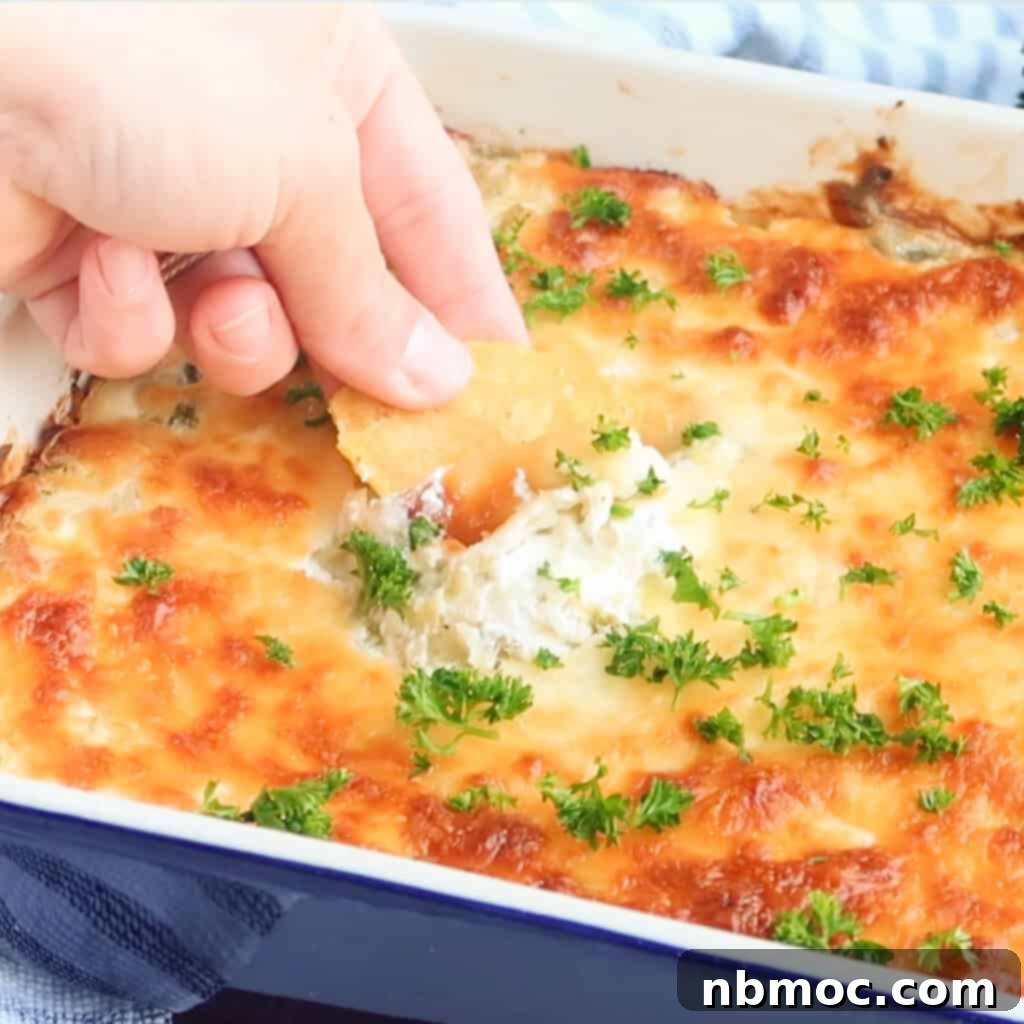 Artichoke dip recipe, corn chip being dipped in jalapeno Artichoke Dip recipe for a Taylor Swift party.