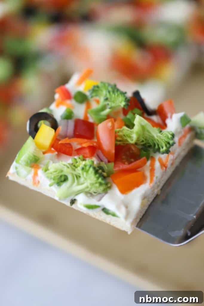 Cold veggie pizza made with pillsbury crescent rolls for the crust, ranch flavored cream cheese, and an assortment of fresh vegetables.