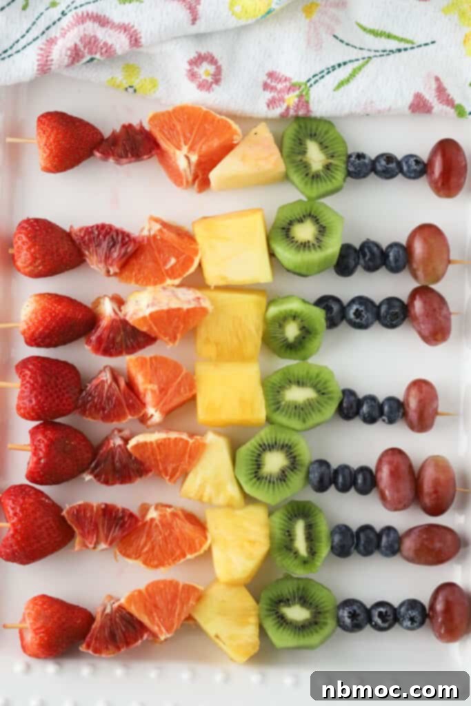 Fruit kabobs rainbow patterns on wooden skewers.