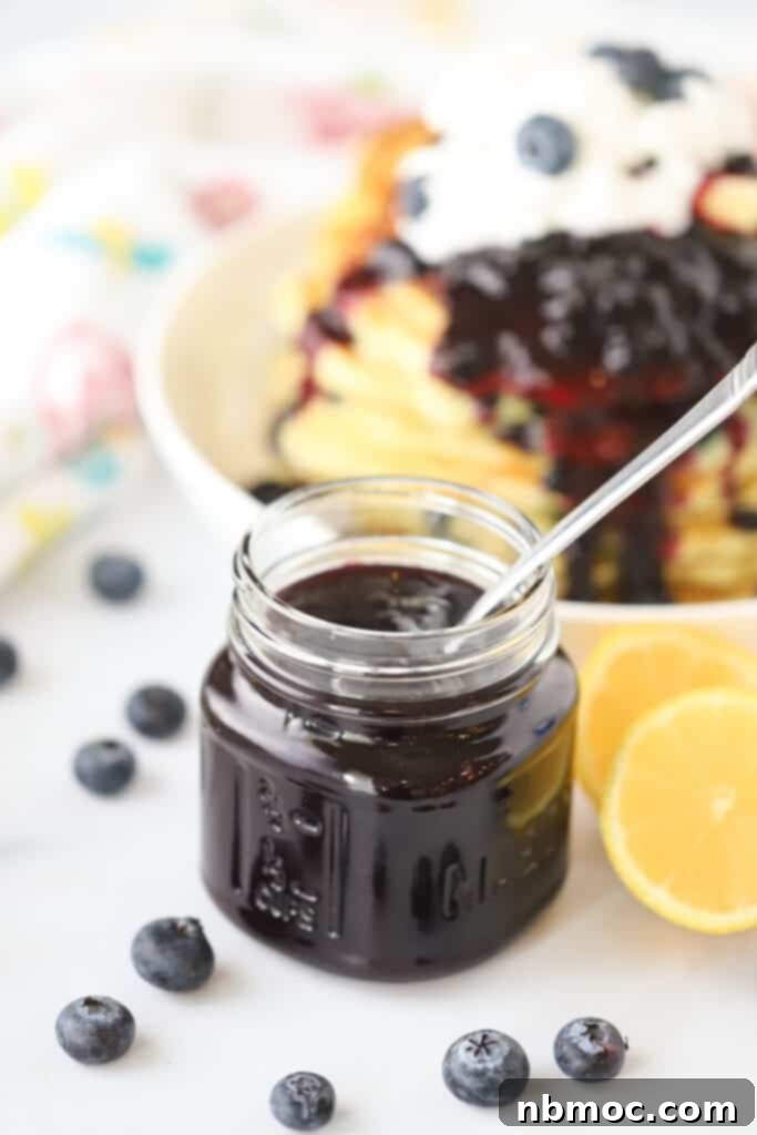 Homemade Blueberry syrup for pancakes in a small mason jar with fresh blueberries.