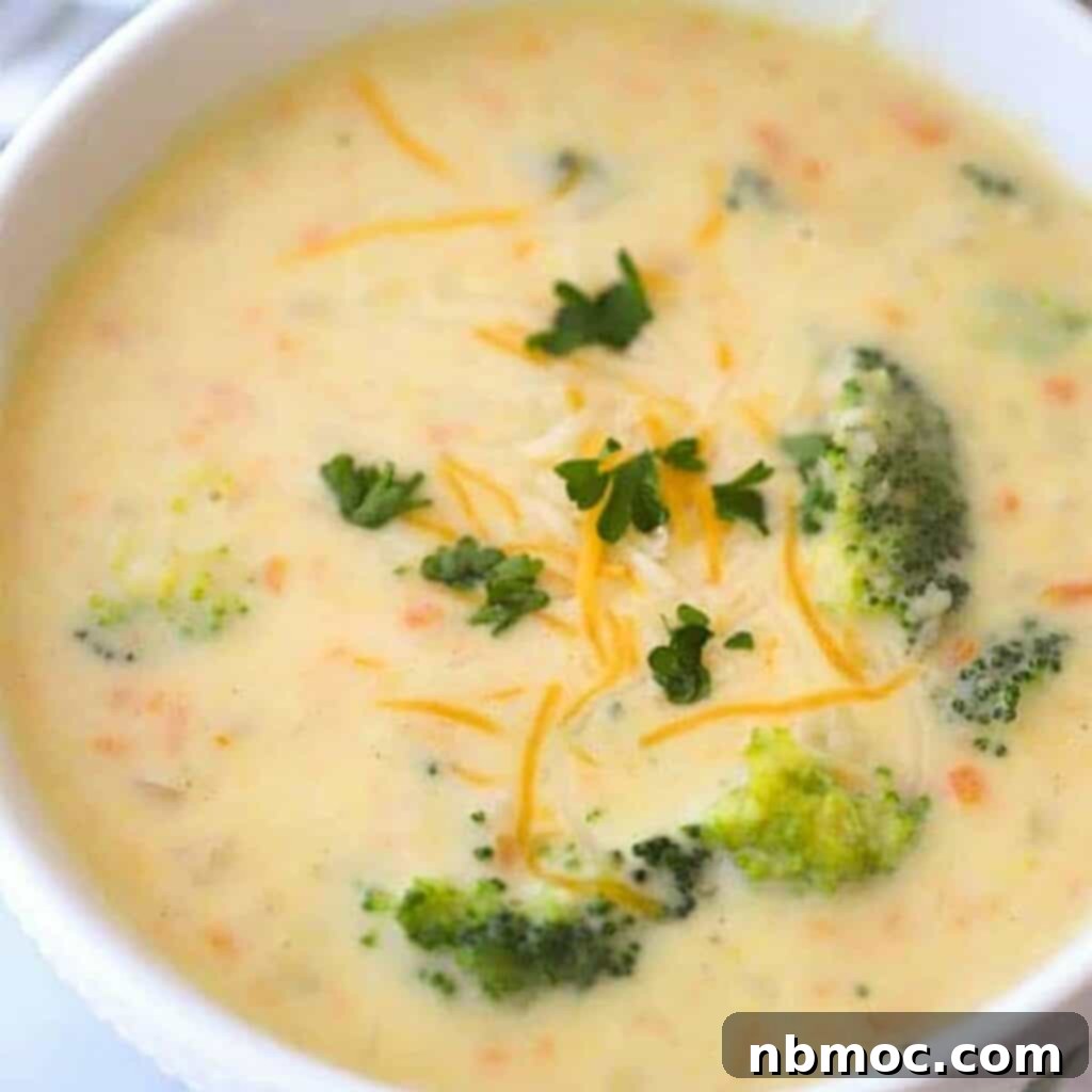 Creamy broccoli potato cheese soup in a white bowl with broccoli garnish, a warm St. Patrick's Day dinner idea.