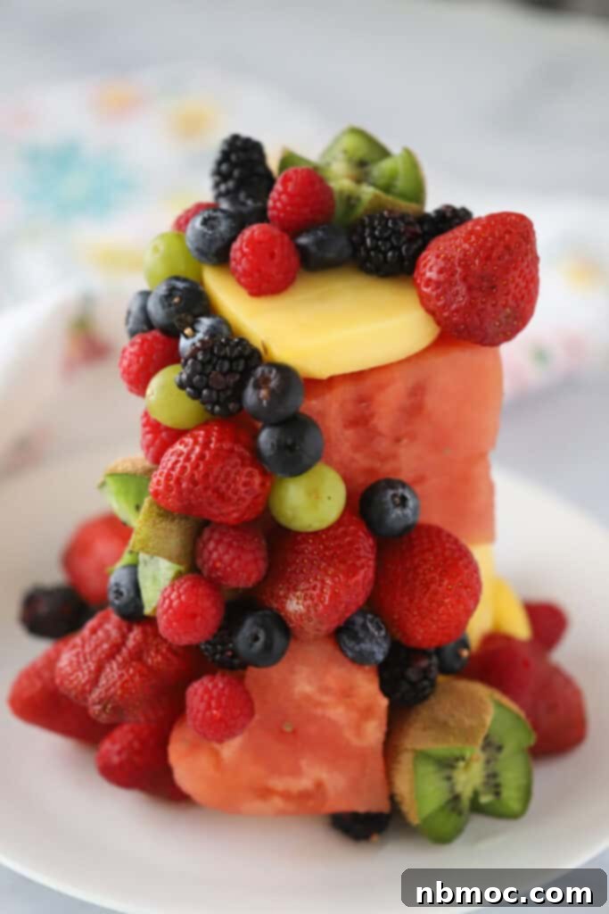 A plate with a cake made out of fresh fruit, featuring a watermelon base and smaller berries and kiwis decorating the edge.