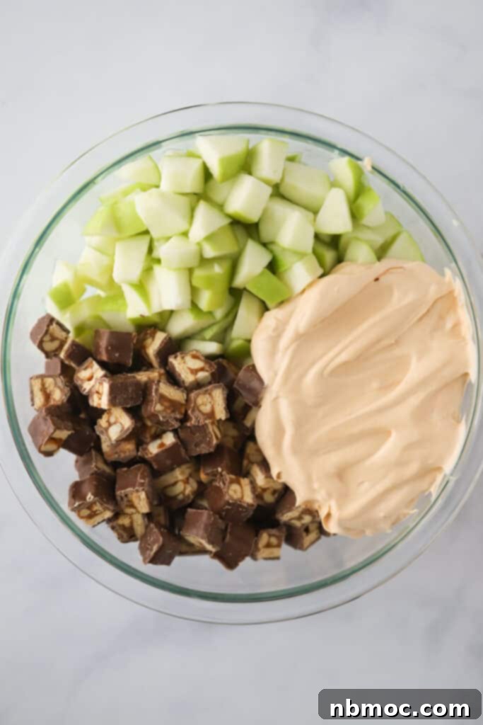 Granny smith apples, diced Snickers bars, and instant pudding in a bowl to make apple fruit salad with snickers.