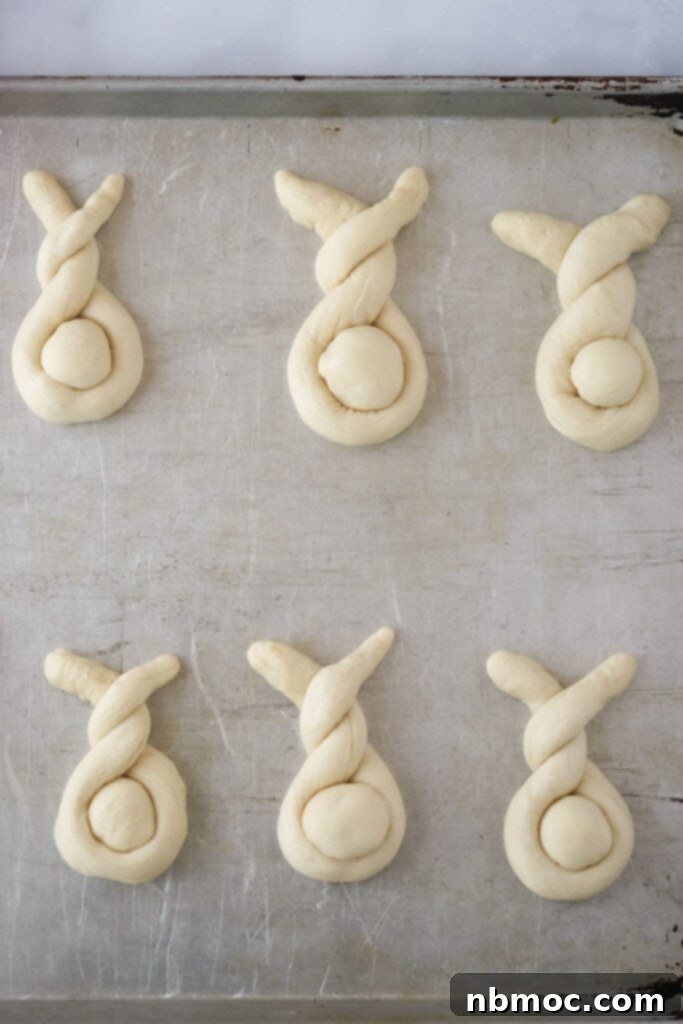 Fluffy Bunny Buns 4 A baking sheet filled with perfectly shaped Easter bunny rolls, ready for the oven.